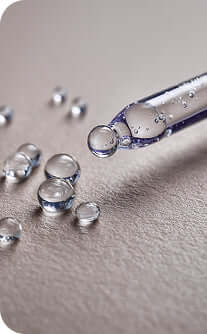 Glass dropper with clear liquid on a gray surface
