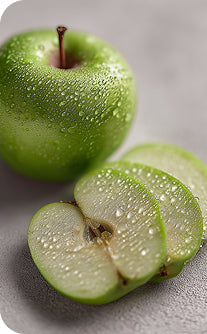 Green apple with water droplets and a sliced green apple on a gray surface