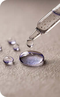 Dropper with a drop of liquid on a textured surface