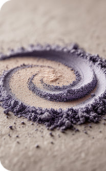 Close-up of a spiral pattern made with purple and beige powder on a textured surface.