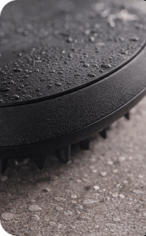 Black hairbrush with water droplets on a textured surface