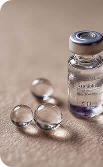 Vial labeled 'Starabil' with droplets on a textured surface