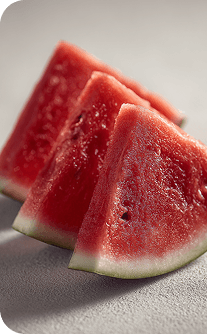 Three slices of watermelon on a light gray surface