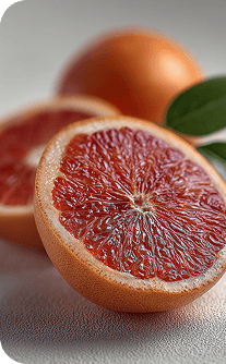 Close-up of a halved blood orange with a whole orange in the background.