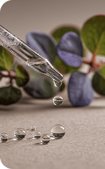 Close-up of a dropper with liquid near leaves on a textured surface