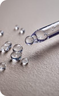 Close-up of a dropper with clear liquid on a gray surface
