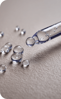 Close-up of a dropper with clear liquid on a gray surface