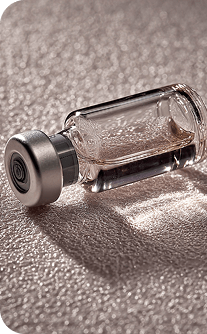 Small glass vial with metal cap on a reflective surface