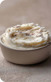 Mashed potatoes in a white bowl on a textured surface