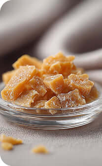 Glass bowl filled with ginger pieces on a neutral background