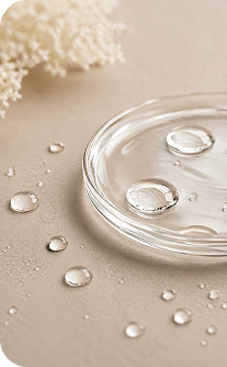 Glass container with water droplets on a beige surface with white flowers