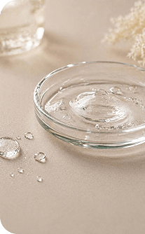 Clear glass bowl with water droplets on a beige surface