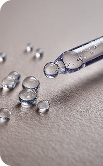 Glass dropper with clear liquid on a gray surface