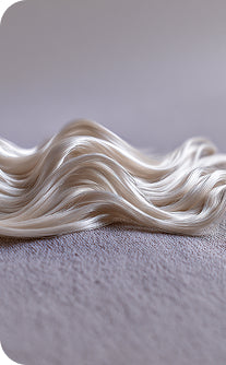 Close-up of wavy white hair extensions on a gray background