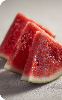 Three slices of watermelon on a light gray surface