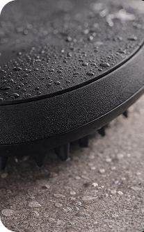 Black hairbrush with water droplets on a textured surface