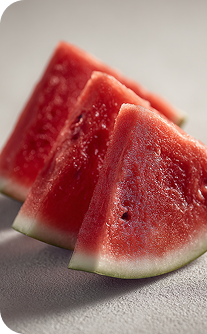 Three slices of watermelon on a light gray surface