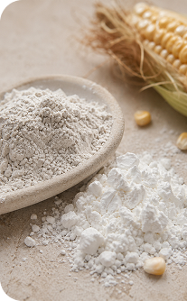 White powder in a wooden spoon with corn kernels on a wooden surface